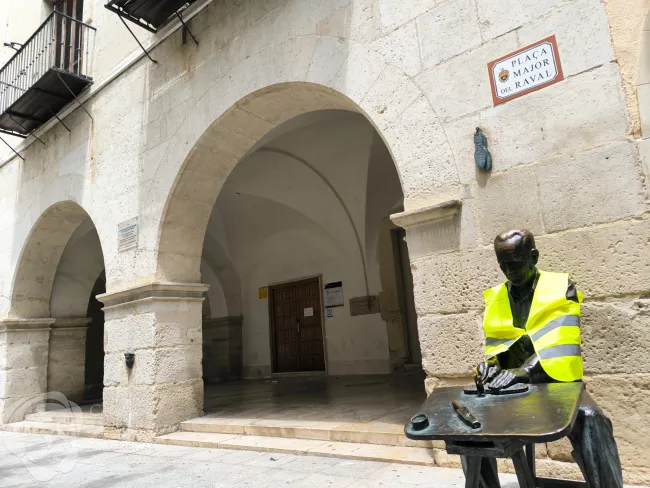 Escultura de El espardenyer (alpargatero) con chaleco reflectante en defensa de la educación pública (2026)